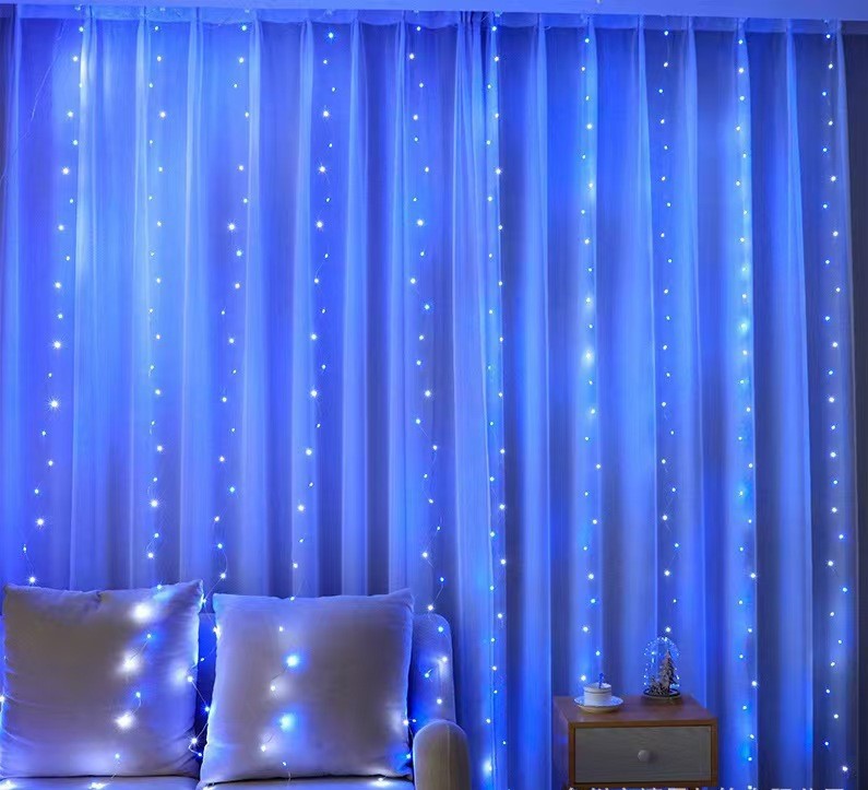 Blue LED curtain lights illuminating a modern living space with white curtains and cozy pillows, perfect for festive or ambient lighting.